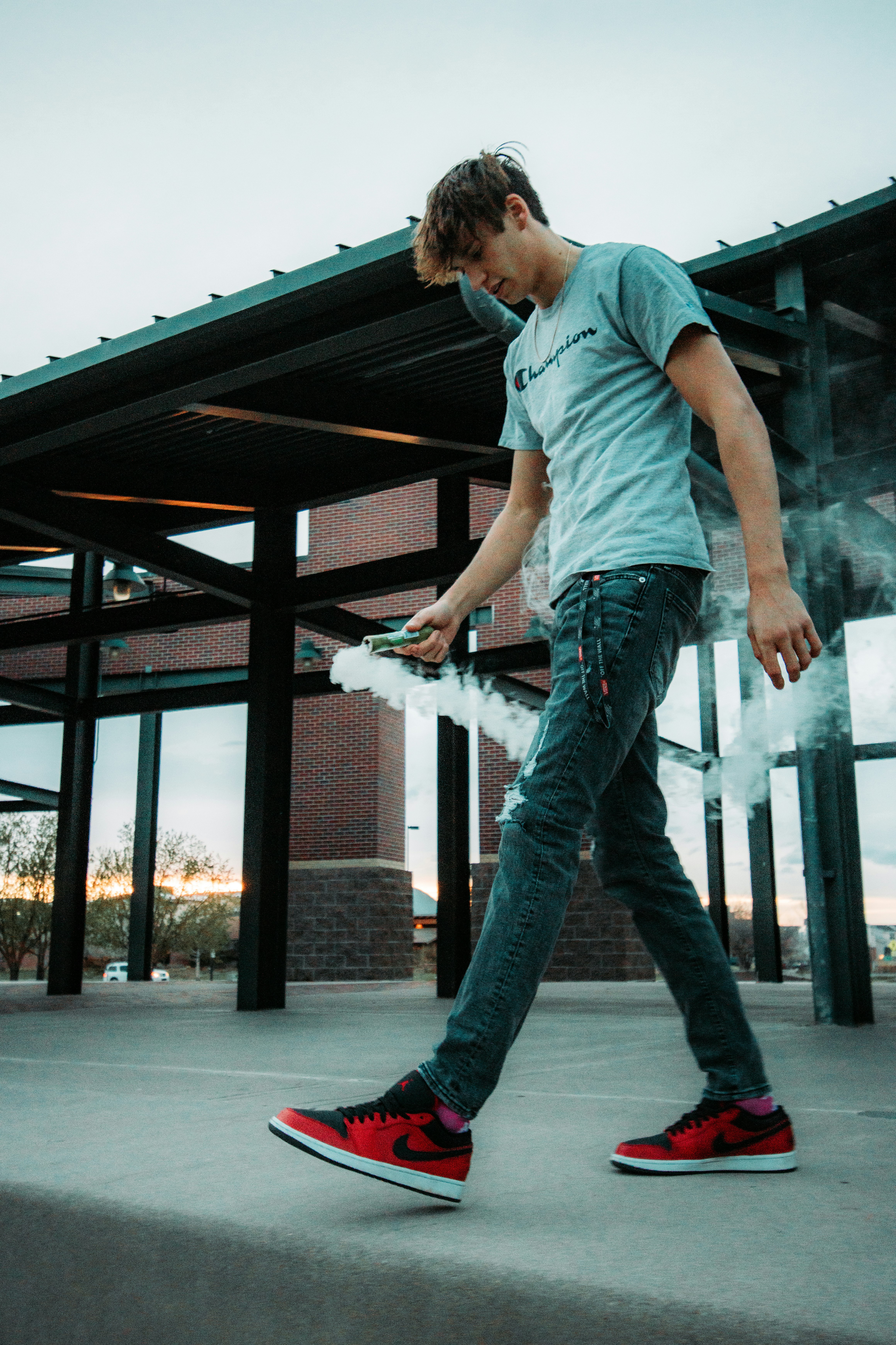 man in blue t-shirt and blue denim jeans standing on gray concrete floor during daytime